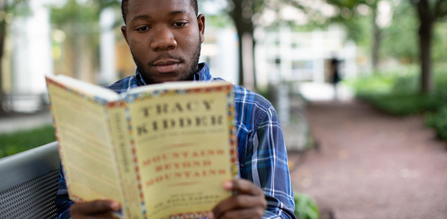 Ancito Etienne Ancito Etienne, PIH board member and cancer survivor from Haiti, reads a copy of Mountains Beyond Mountains.