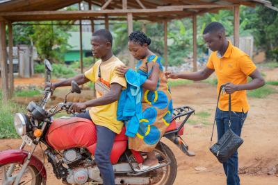 Anthony N. Kollie accompanies Aletha Walker to the Pleebo Health Center on a motorbike.