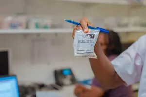 A small zip-top bag of prescription medicine being held out it one hand.