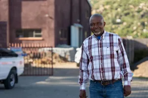 Paul Soko, PIH Lesotho’s infrastructure and maintenance coordinator, on the grounds of Botšabelo Hospital in April 2024. Soko stands on the pavers he designed and laid; and behind him is the warehouse that he helped construct.