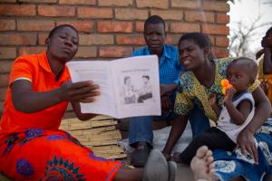 CHW in Malawi reading to a family