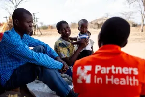 Two men and one woman holding a baby are speaking to each other in Malawi
