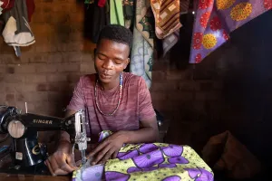Patrick Francis, a 19-year-old ASPIRE Project participant trained in tailoring, uses his sewing skills to make a living and serve his community. 