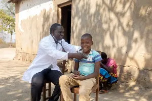 Clinical team member Henderson Masanjala performing a follow-up examination on Promise Douglas, a 9-year-old patient recovering from heart surgery.