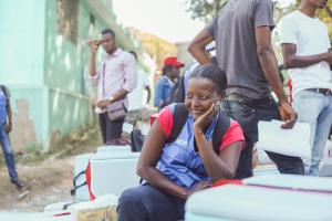 Nadine, a Community Health Worker, sitting with boxes of cholera vaccines, ready to be distributed in various sites and communities in Haiti.