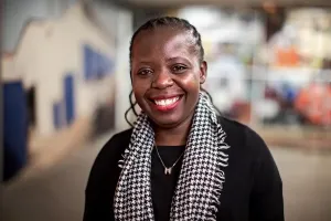Basimenye Nhlema smiles at the camera in a black shirt with a black and white scarf