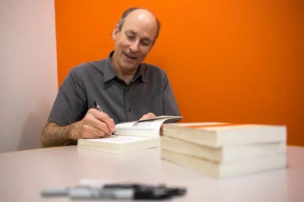 Tracy Kidder signing his book on a white table.