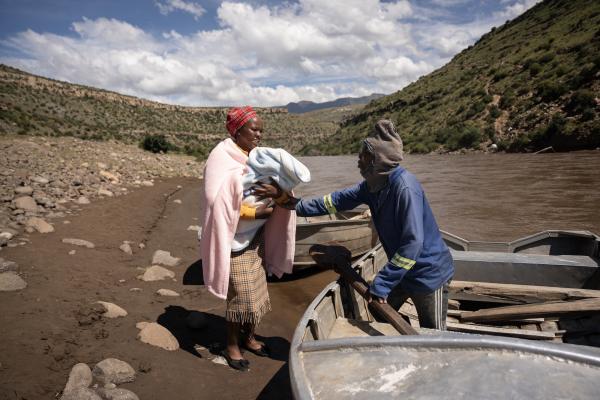A new mom ‘Masebabatso Mokatlela from Ha Ramokatlela is being assisted to cross the river using a boat after a baby was born the day before.