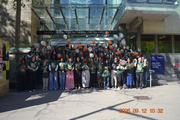 A group of 50+ students huddles outside of Bahen Centre in Toronto. They are throwing balloons into the ait. 