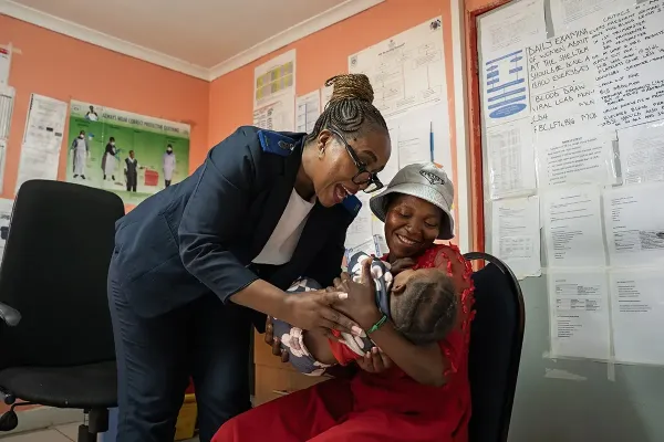 Partners In Health nurse Thandy Ketsia Tsoke, left, plays with Tlhokomelo, the 10-month-old daughter of Mathabelang Motselekatse.