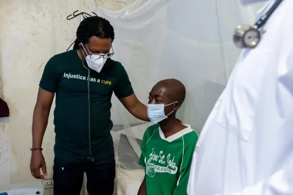 Dr. Maxo Luma, executive director of PIH Liberia, stands with Joe, a 24-year-old carpenter with MDR-TB.