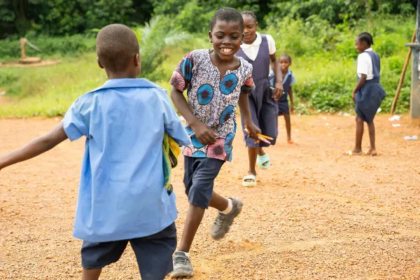 Five smiling students play together outside their school in Liberia