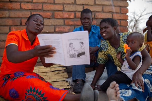 CHW in Malawi reading to a family