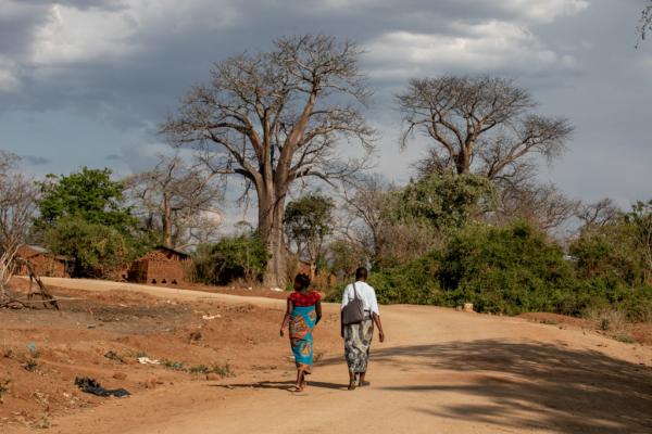 APZU Community Health Worker Grace Mgaiwa (right) walks with Eliza Kazembe (left) during a maternal health home visit near PIH-supported Lisungwi Community Hospital in Neno District, Malawi. Eliza said her health at nine months was good and she was excited to give birth, but joked that it felt like she had been due “forever.” She planned to go to the maternal waiting home at Lisungwi Community Hospital in about a week, to await delivery.