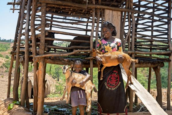 Milliam Kerekesa and her nephew Stanley carry goats provided through PIH Malawi's Poser Goat Seed Program, promoting sustainability and community empowerment in Neno.