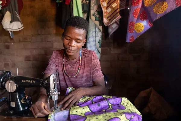 Patrick Francis, a 19-year-old ASPIRE Project participant trained in tailoring, uses his sewing skills to make a living and serve his community. 