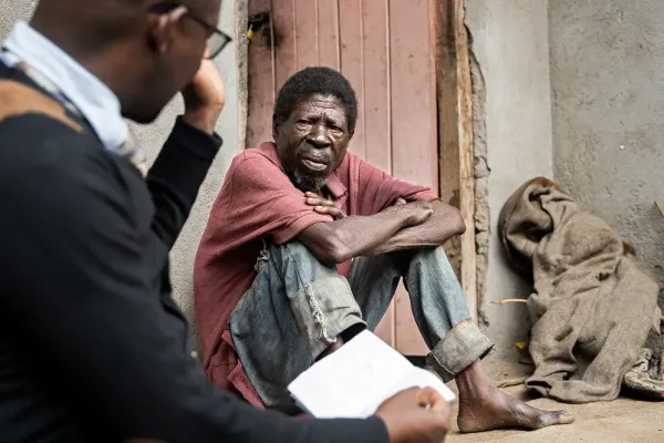 Saulos Metio, a tuberculosis (TB) patient, speaks with Charles Marshal, Nutrition Coordinator at Abwenzi Pa Za Umoyo (APZU).