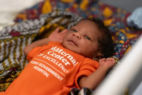 Newborn resting on patterned blanket in a hospital setting.
