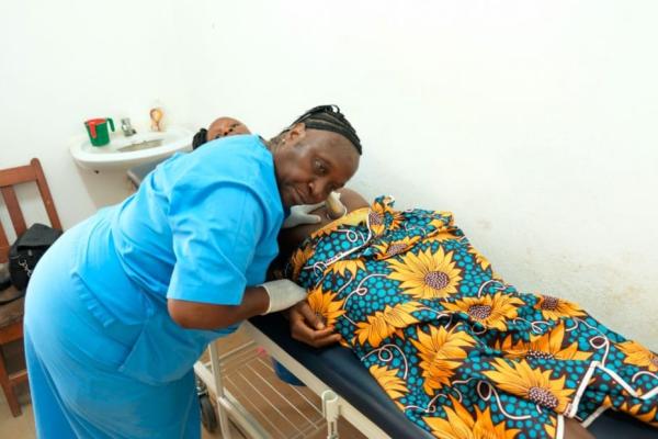 Birth attendant listens to pregnant patient's fetal heart rate