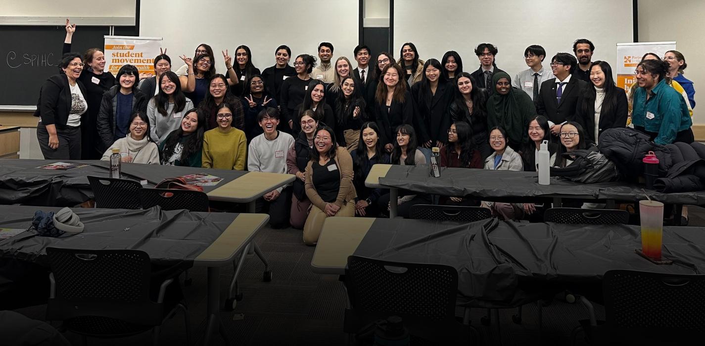 A group of students gather at the front of a university classroom for a photo at the end of the case competition