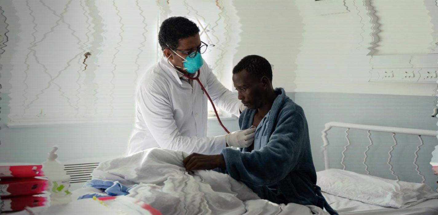 A doctor examines a patient in a hospital bed in Lesotho.