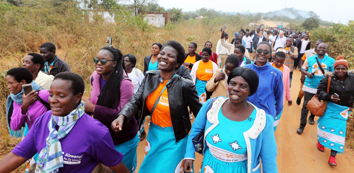 A crowd of people in bright blue uniforms gather, walking together on a red road.