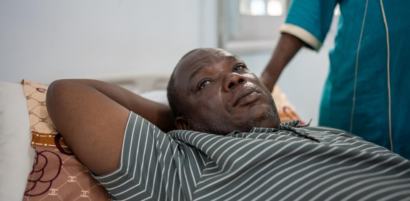 Alusine Sesay lying down at the waiting room for the ambulance after checkup.