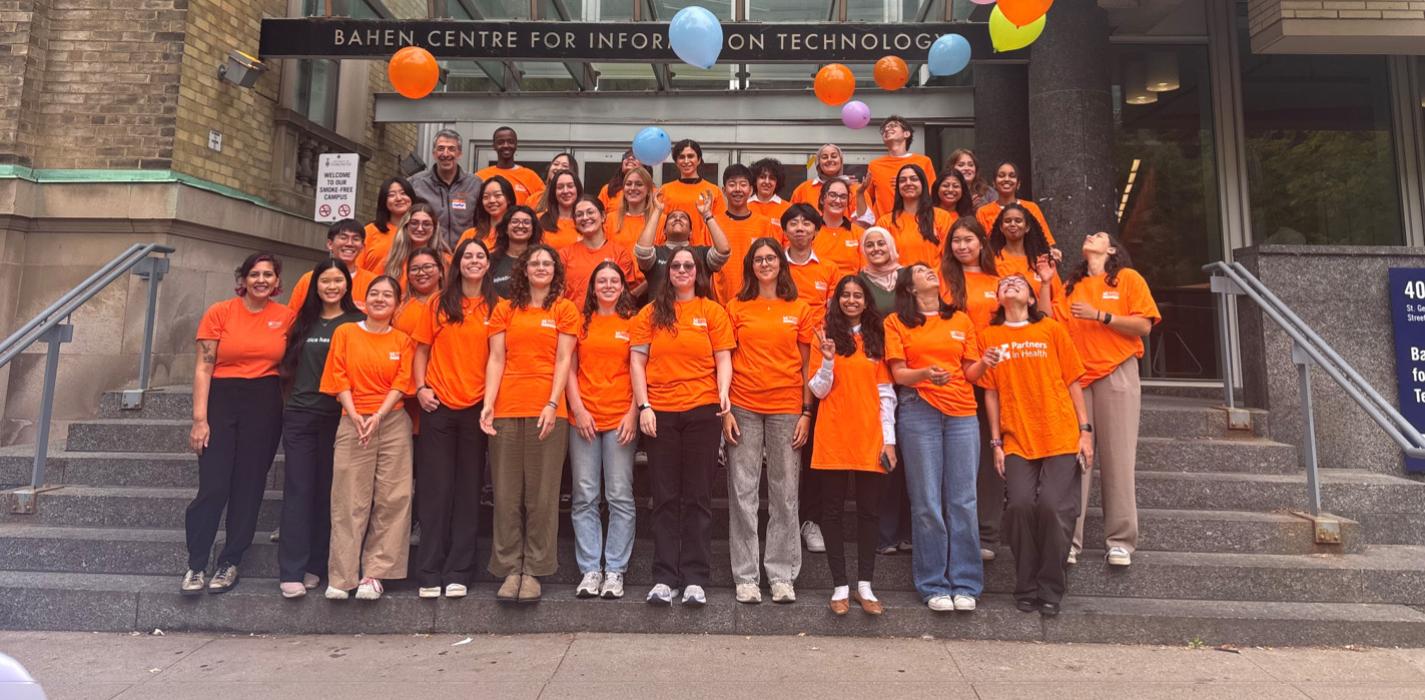 Students in orange shirts posing for a photo outside U of T building.