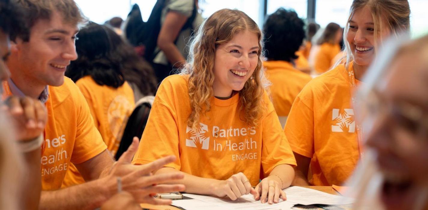 Students wearing orange t-shirts sitting at a table talking