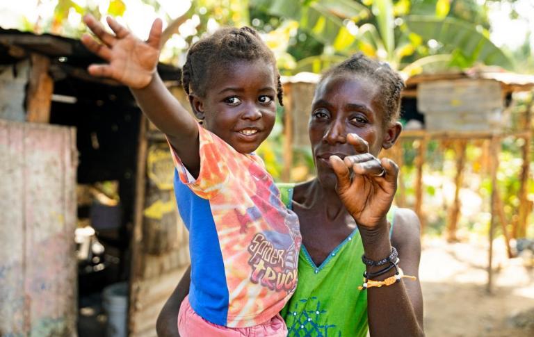 Joléne carries her young son Raphaël, who recovered from severe malnutrition after receiving medical treatment and therapeutic food through Partners In Health programmes in Haiti.