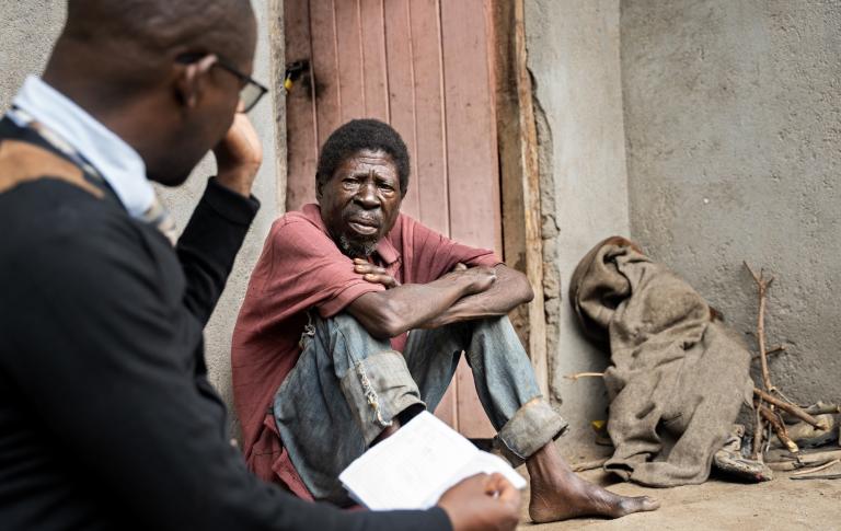 Saulos Metio speaks with Charles Marshal, at PIH Malawi, during a home visit as part of his ongoing treatment and nutritional support.