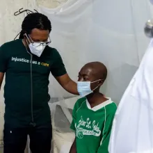 Dr. Maxo Luma, executive director of PIH Liberia, stands with Joe, a 24-year-old carpenter with MDR-TB.