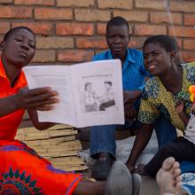 CHW in Malawi reading to a family