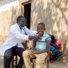 Clinical team member Henderson Masanjala performing a follow-up examination on Promise Douglas, a 9-year-old patient recovering from heart surgery.