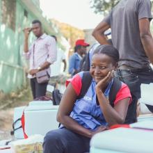 Nadine, a Community Health Worker, sitting with boxes of cholera vaccines, ready to be distributed in various sites and communities in Haiti.