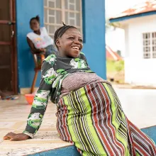 Sia Fengai, 26, sits on the front porch of the maternal waiting home at Wellbody Clinic in Kono District.