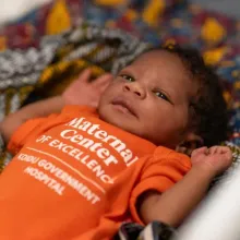 Newborn resting on patterned blanket in a hospital setting.
