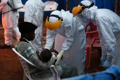 Healthcare workers in personal protective equipment assess a boy.