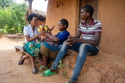 Nursing Officer at Neno District Hospital, visits Agness George and her husband, Daniel George, as they carry their newborn son.