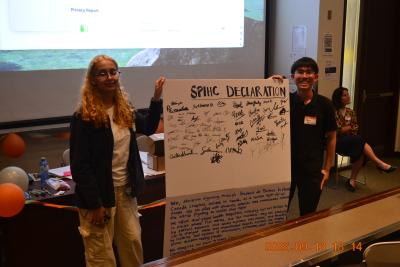 Two students hold a poster board up. They are smiling.