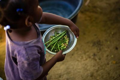 Child holding green beans. 