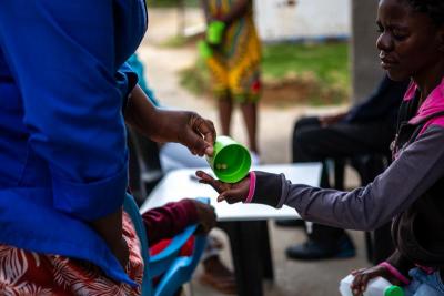 Treatment supporter Rethabile Setenane administers medication to Lerato Leqhaloha.