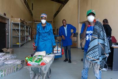 Masingoaneng Kolosoa (left), a treatment supporter for Kaizer Mahapa (right), picks up a food package from the warehouse at PIH-supported Botšabelo Hospital.