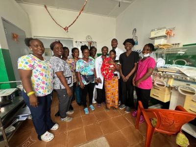 Doctors wearing white lab coats and nurses wearing scrubs smiling in group picture