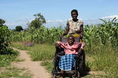 Regina's mother Enres, pushes her in her wheelchair through a grassy area