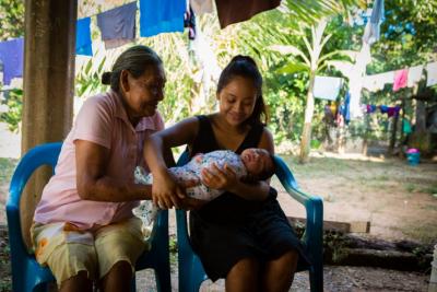 Mother holds newborn in front of midwife in Mexico