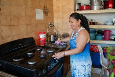 Woman smiling and standing over stove in kitchen
