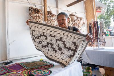 Elia Bardales displays a patterned textile at a market stall.