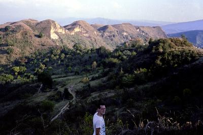 A photo of a young Paul Farmer in nature, in front of a mountain range.