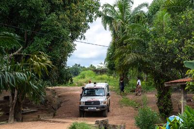 An ambulance driving on a dirt road surrounded by trees.